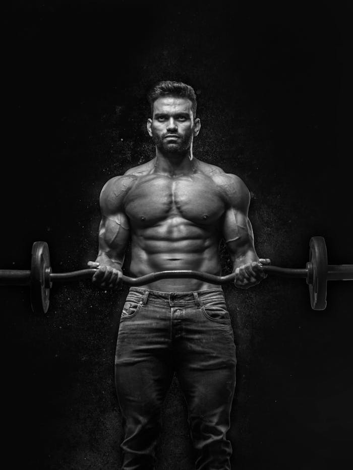 gallery-06 Black and white portrait of a muscular man lifting weights, showcasing strength and fitness.