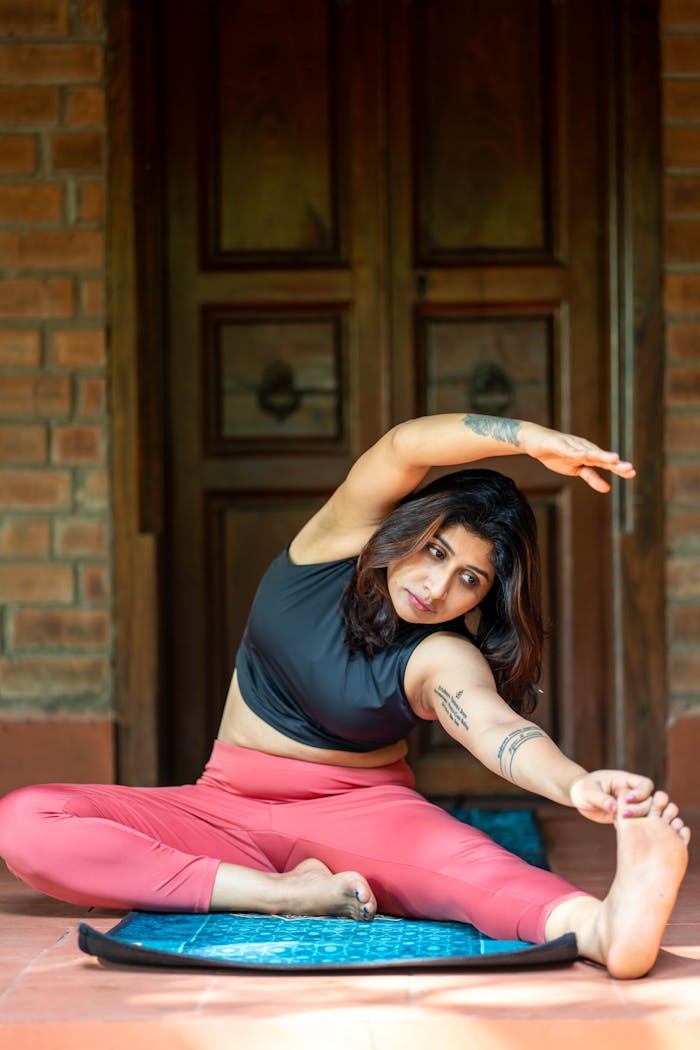 cta-02 Woman stretching in seated yoga pose indoors with brick background.